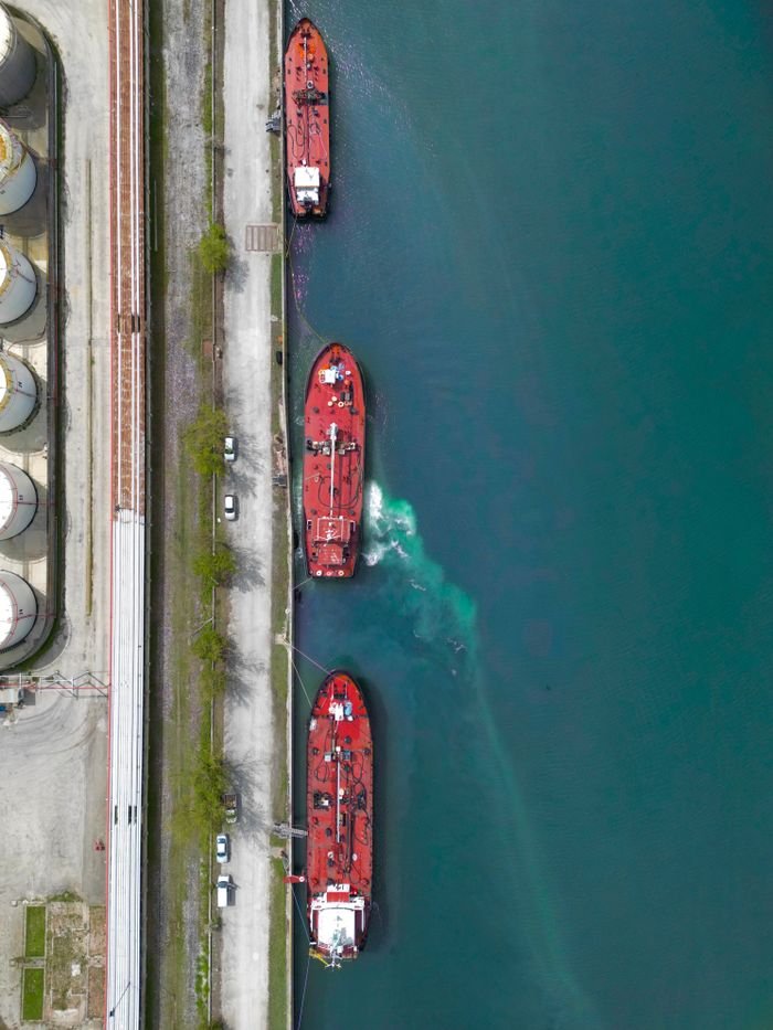 Top-down aerial shot of ships moored at a port in Ravenna, Italy, showcasing industrial waterfront activity.