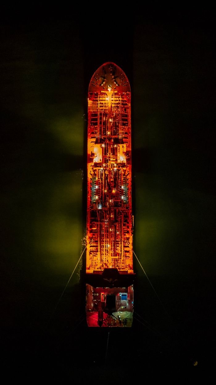 The Art of Drawing Readers In: Your attractive post title goes here Drone shot of an illuminated cargo ship at night, showcasing its vibrant lights.