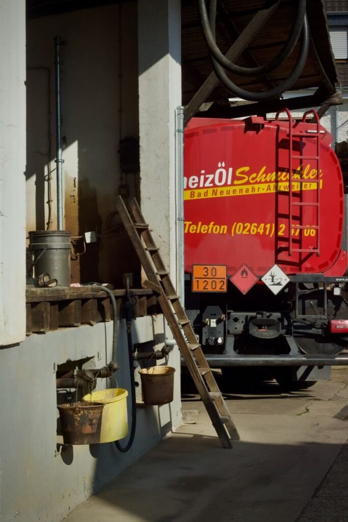 A fuel truck parked at an industrial site with hoses and containers.