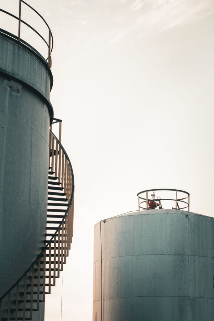 View of industrial silos with spiral staircase during sunrise, offering dramatic silhouette.