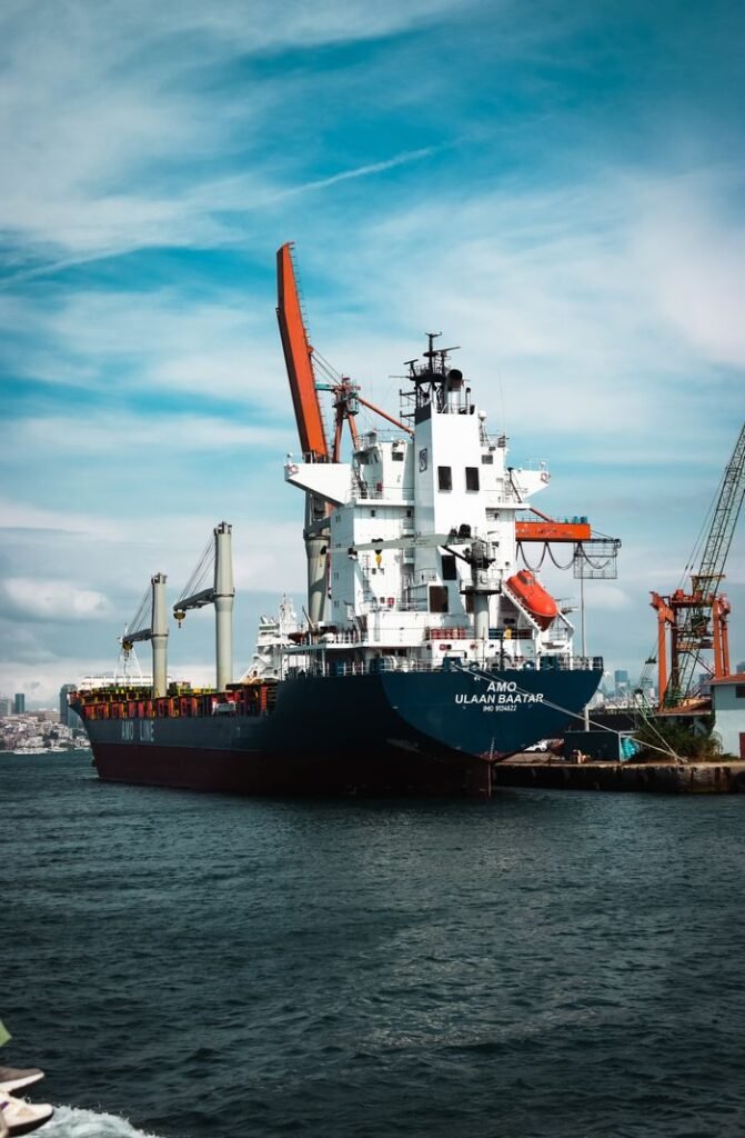 Large container ship docked at bustling Istanbul harbor, with industrial cranes and blue skies.